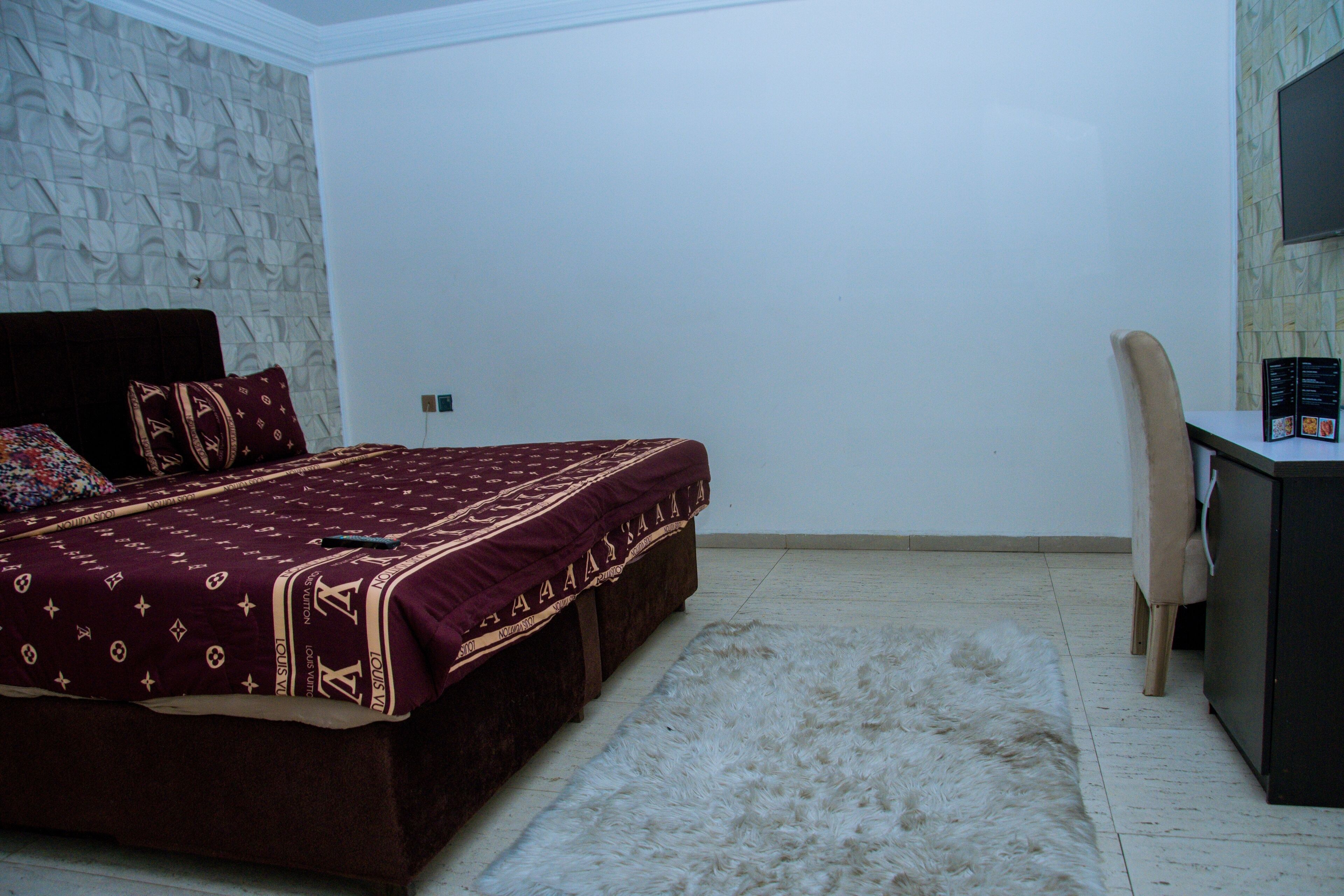 Un dormitorio con una cama grande, un escritorio y una silla.