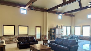A spacious living room with leather sofas, a wooden coffee table, and a stone accent wall. - Spacious 6-bedroom hilltop cabin in tranquil Oracle (Oracle)