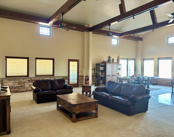 A spacious living room with leather sofas, a wooden coffee table, and a stone accent wall. - Spacious 6-bedroom hilltop cabin in tranquil Oracle (Oracle)