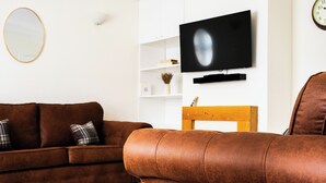 A living room with a brown sofa, a television mounted on the wall, and a wooden chair. - Cozy, Family Friendly ,Home Away from Home in Aveley, Thurrock (Aveley)