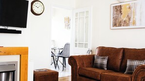 A living room with a brown sofa, a flat-screen TV, a fireplace, and a dining area in the background. - Cozy, Family Friendly ,Home Away from Home in Aveley, Thurrock (Aveley)