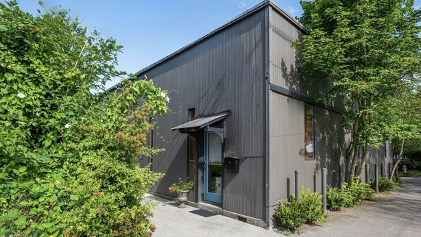 A modern building with a dark exterior, a door with a blue frame, and a small porch area. - Boho Studio on 8th Ave West | Queen Anne, Seattle Near Stadium (Seattle)