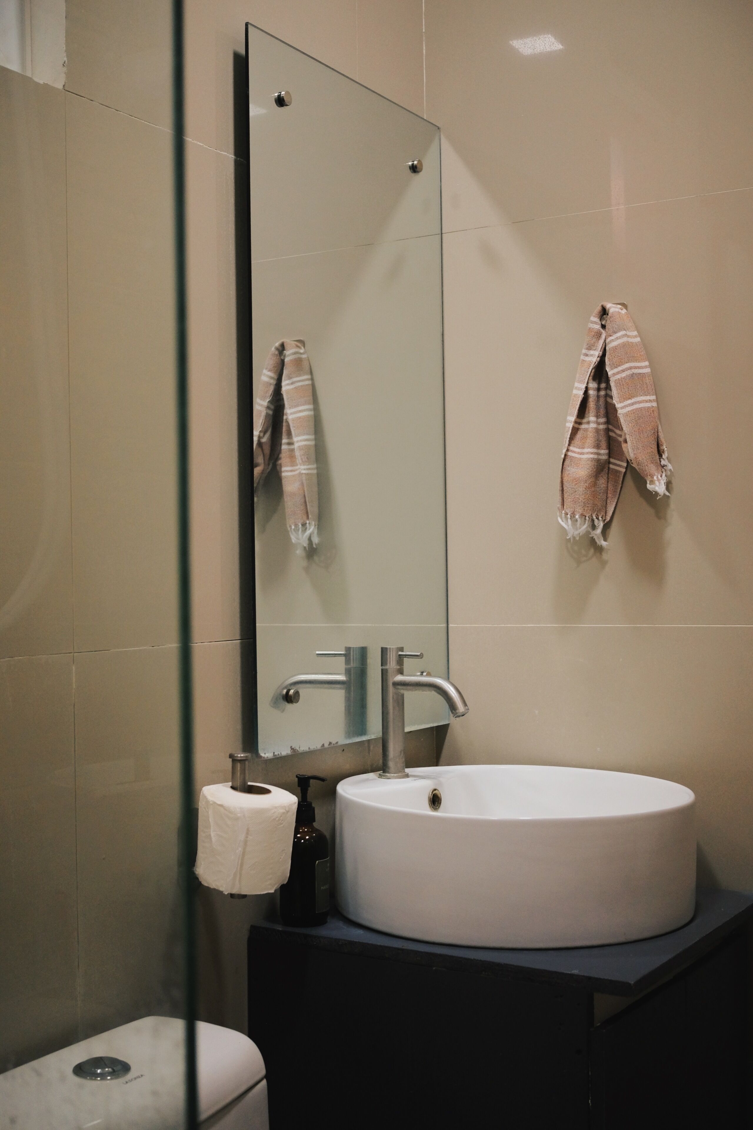 A bathroom with a round sink, a mirror, and a towel rack.