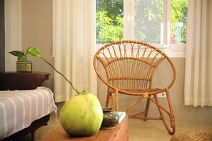 A wicker chair, a bed, a table with a green fruit, and a window with curtains. - 2BR Laid Back Apartment, Near Beach (San Fernando)