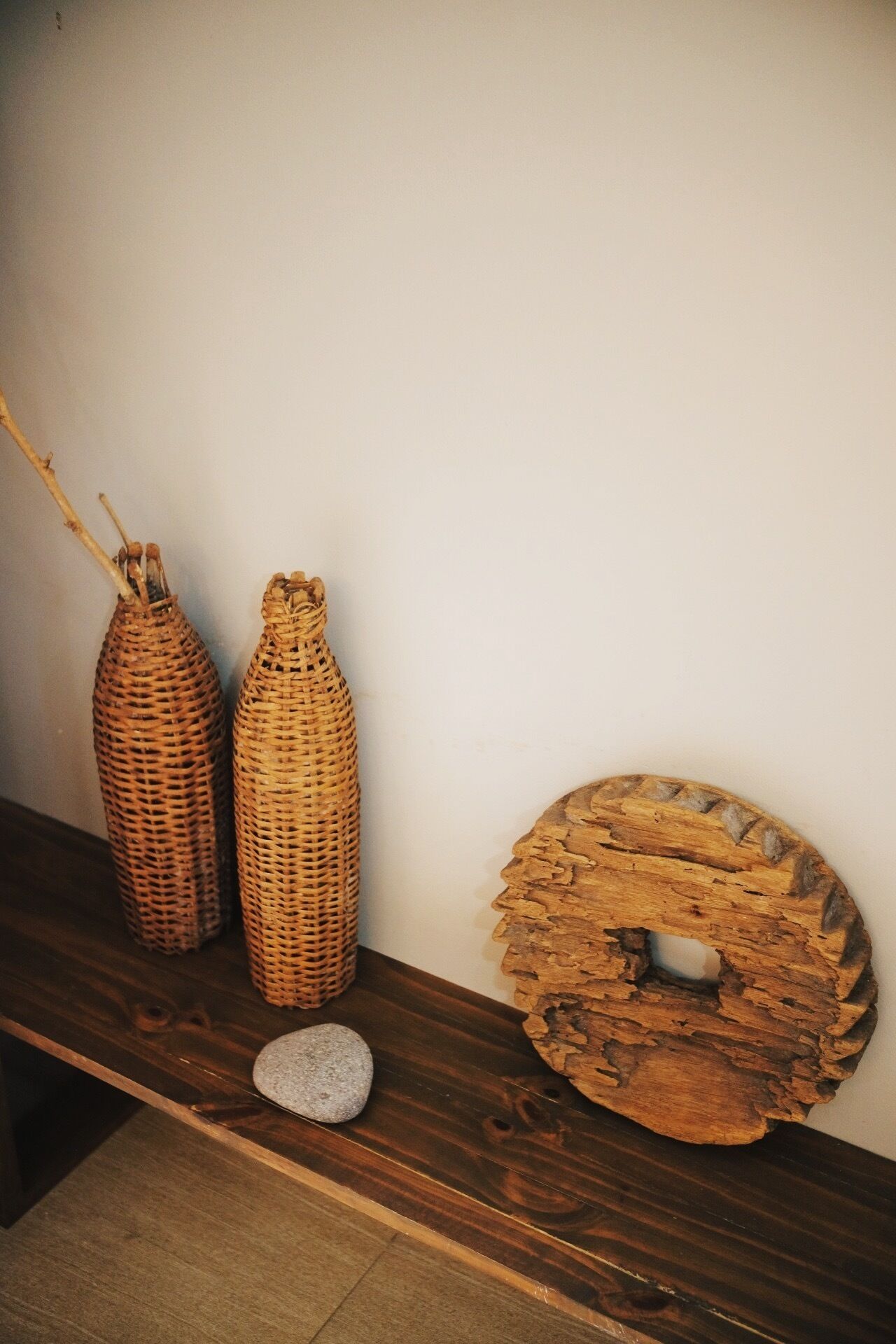 Une étagère en bois avec trois vases en osier et un élément décoratif circulaire en bois.