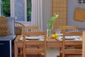 A dining table set with plates, glasses, and a vase with a plant and lemons. - 2BR Laid Back Apartment, Near Beach (San Fernando)