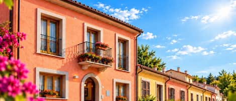 Una hilera de edificios color terracota con balcones, arcos y macetas.