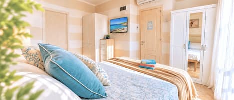 Un dormitorio con cama, armario, televisor y puerta que da a otra habitación.