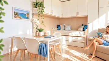 Een moderne woonkamer met een bank, een eettafel met stoelen en een keukenhoek.