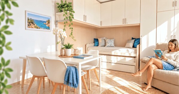 A modern living room with a sofa, a dining table with chairs, and a kitchen area. - Vento Mare Apartments & Suites-Palau (Palau)