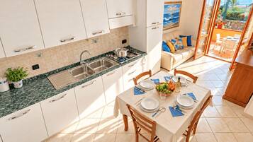 Una cocina moderna con comedor, vistas al exterior y un balcón con mesa lista para comer.