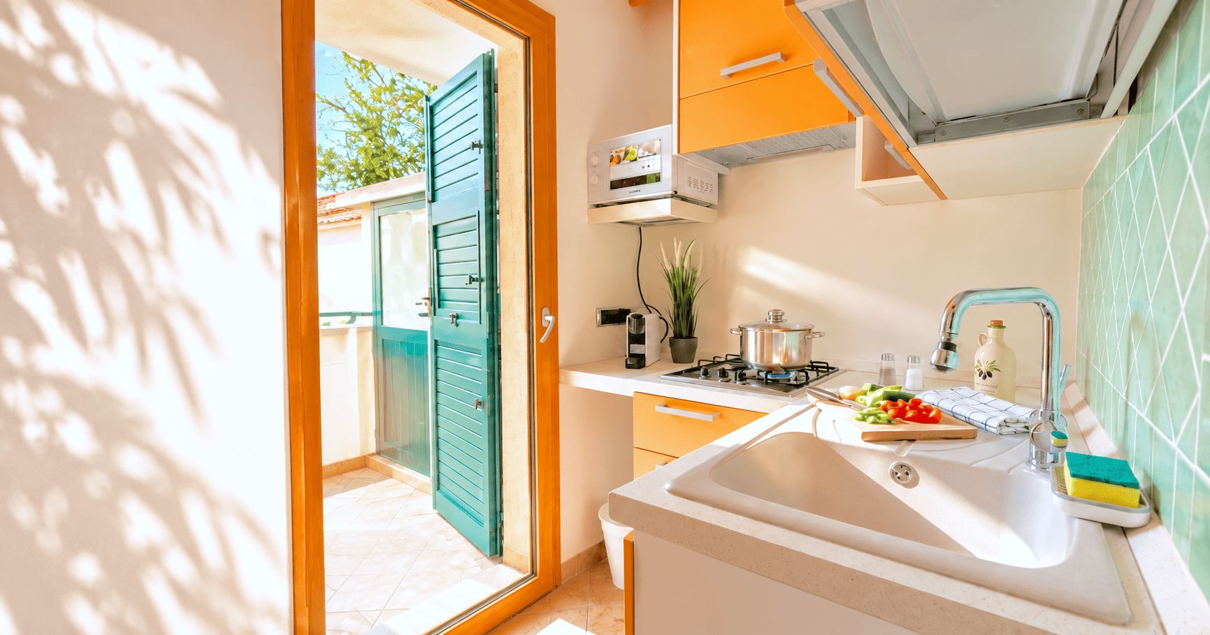 Une cuisine de taille réduite, équipée d’une cuisinière à gaz, d’un évier et d’un petit plan de travail.