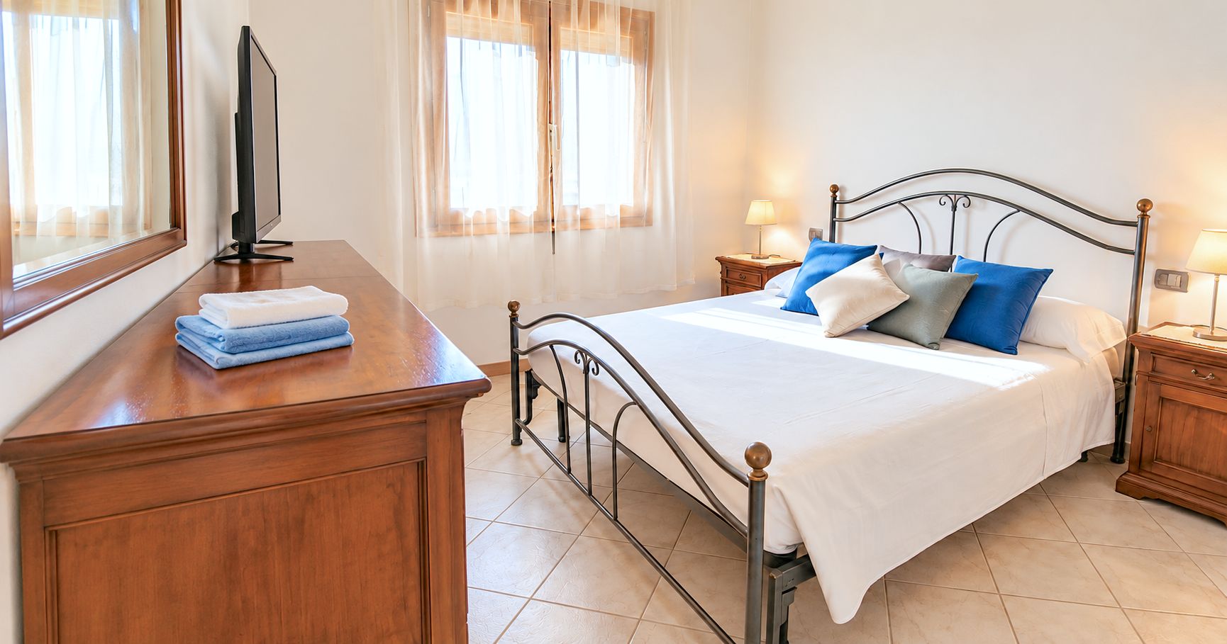Een slaapkamer met een bed, nachtkastjes, een flatscreen televisie en een houten dressoir.