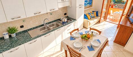 A modern kitchen with white cabinets, a marble countertop, and a dining area with a table set for four.