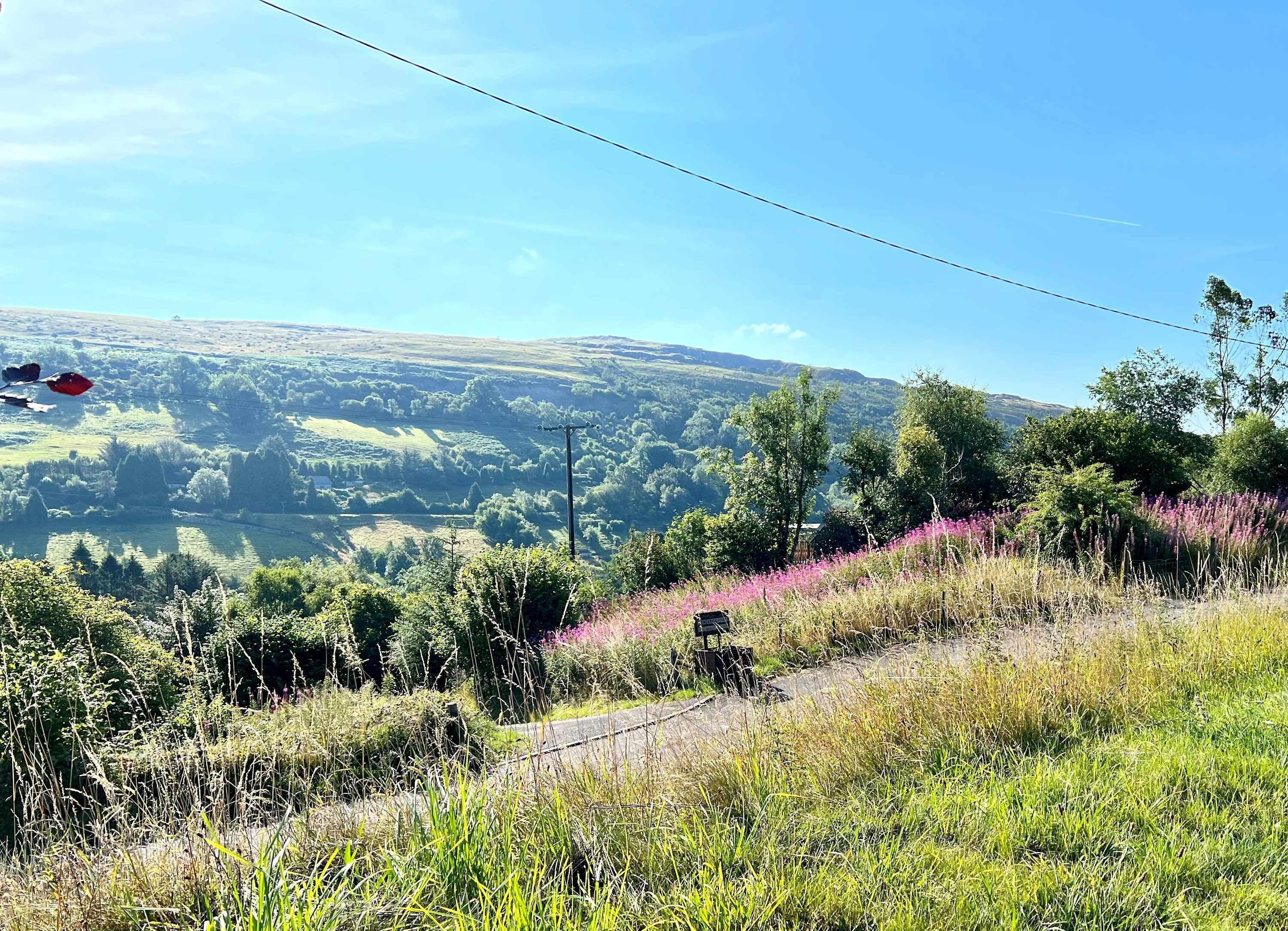 Un paysage magnifique offrant une vue dégagée sur des collines ondoyantes et un plan d’eau au loin.