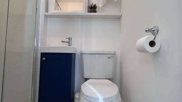 Une salle de bain avec des toilettes, un lavabo et une douche.