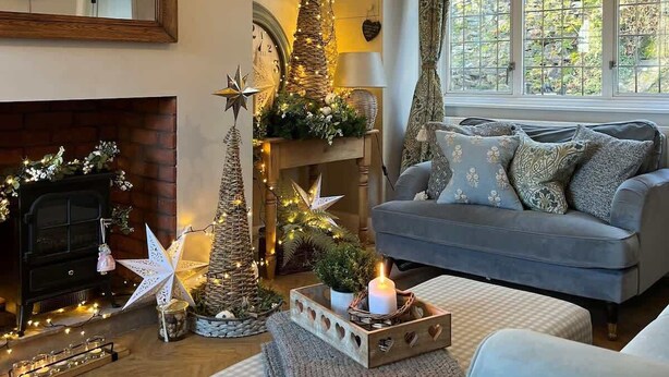 Ein gemütliches Wohnzimmer mit Kamin, einer Couch und dekorativen sternförmigen Ornamenten.