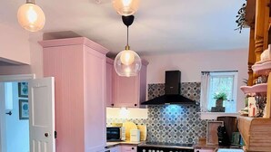 Eine Küche mit rosafarbenen Schränken, einem Holzespeisetisch und einem Herd.