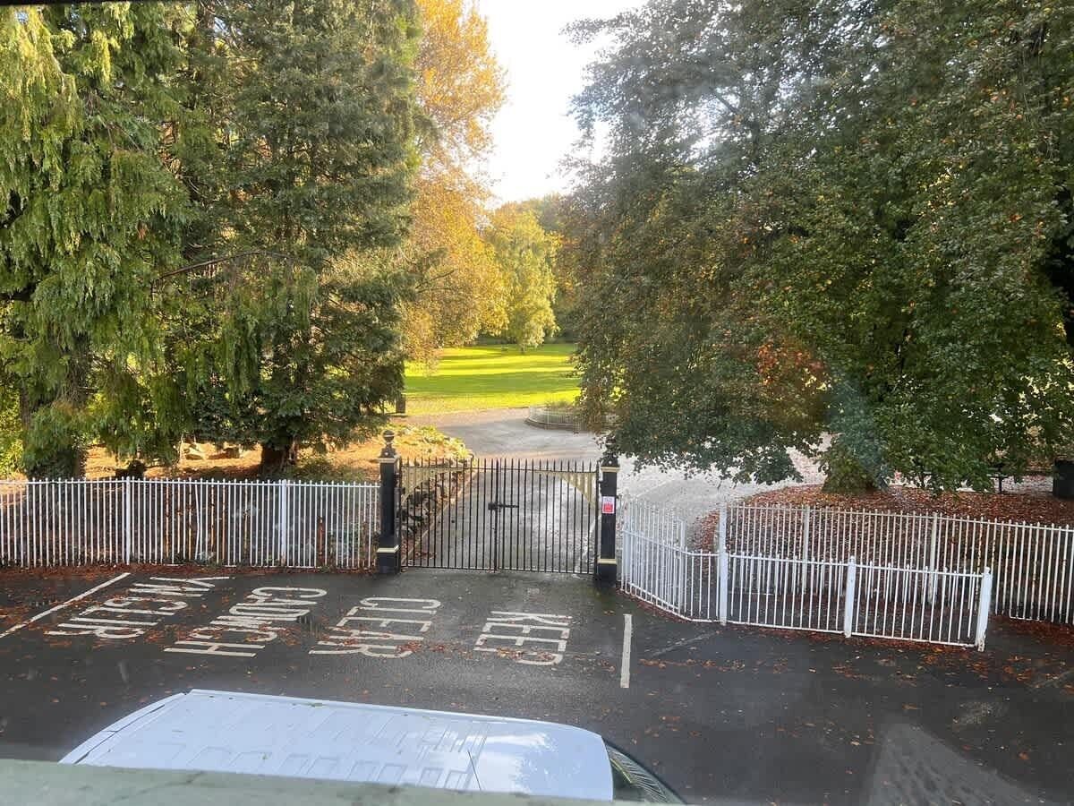 Ein durch einen Zaun gesicherter Parkbereich mit einem deutlichen Weg zu einem grünen Feld.