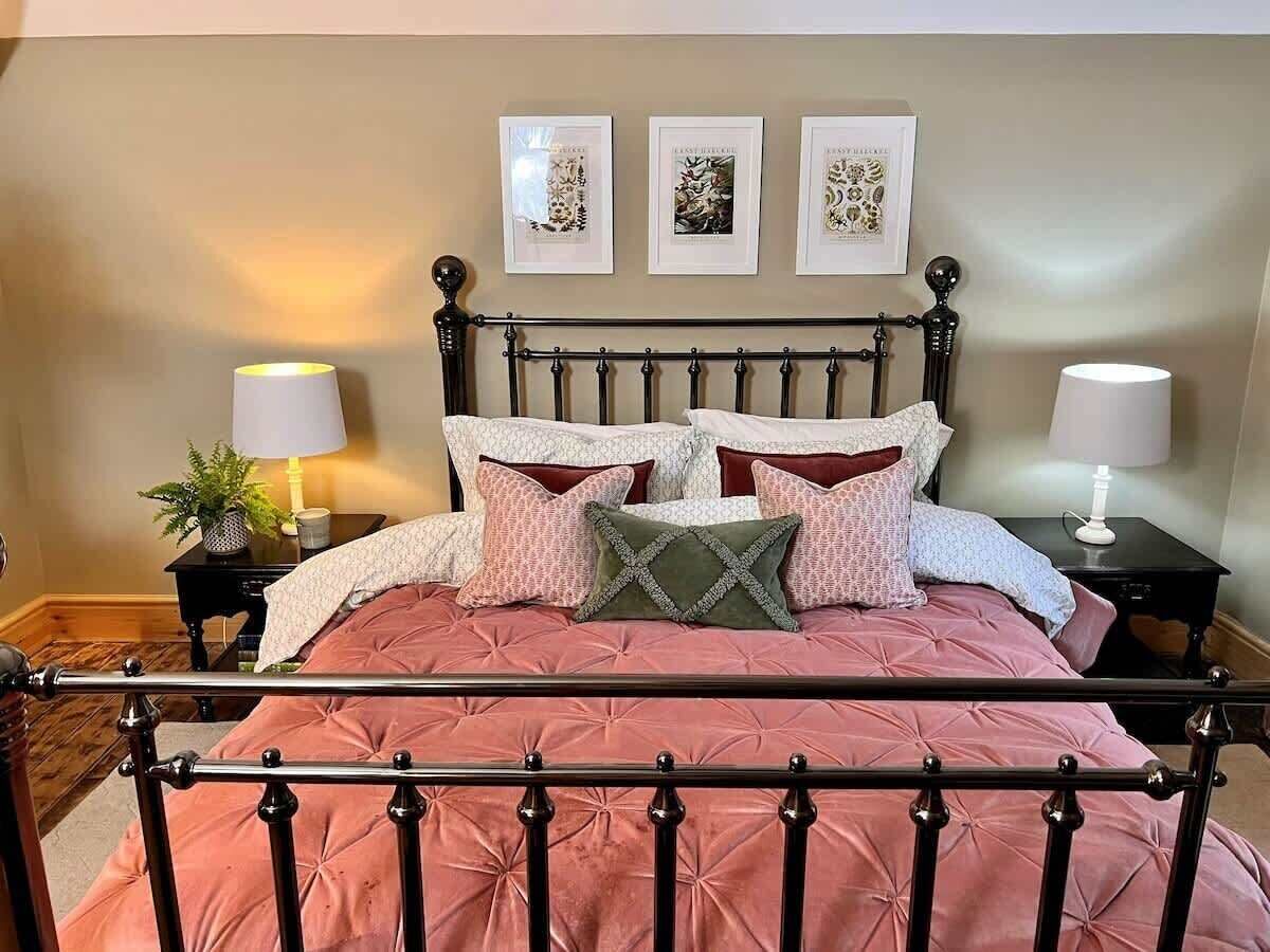 A bedroom with a bed, two bedside tables, and three framed pictures on the wall.