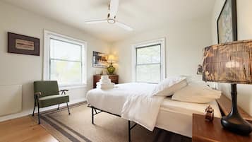 A bedroom with a bed, a chair, a lamp, and a ceiling fan.