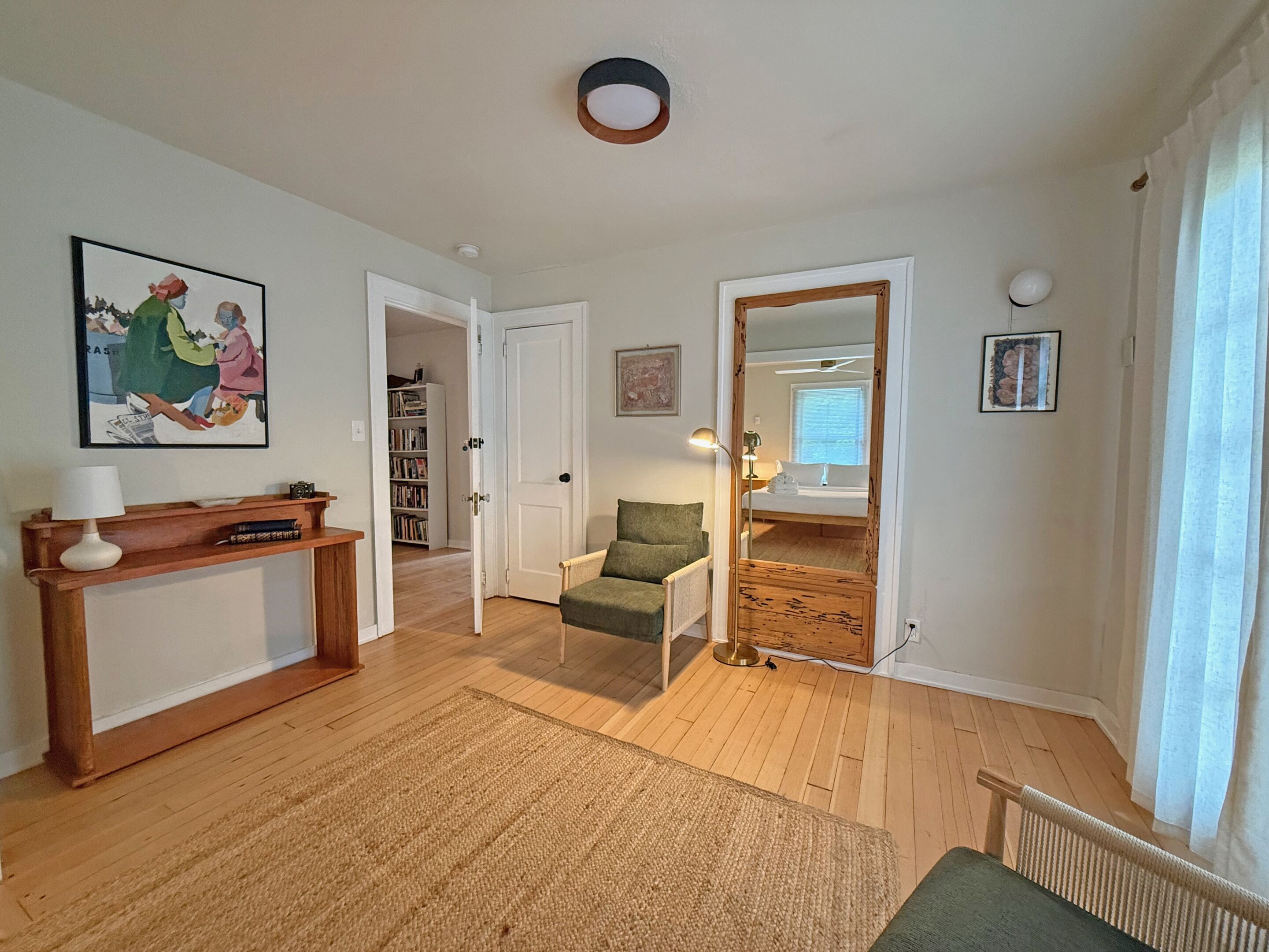 A living room with a sofa, a coffee table, a bookshelf, and a door leading to another room.
