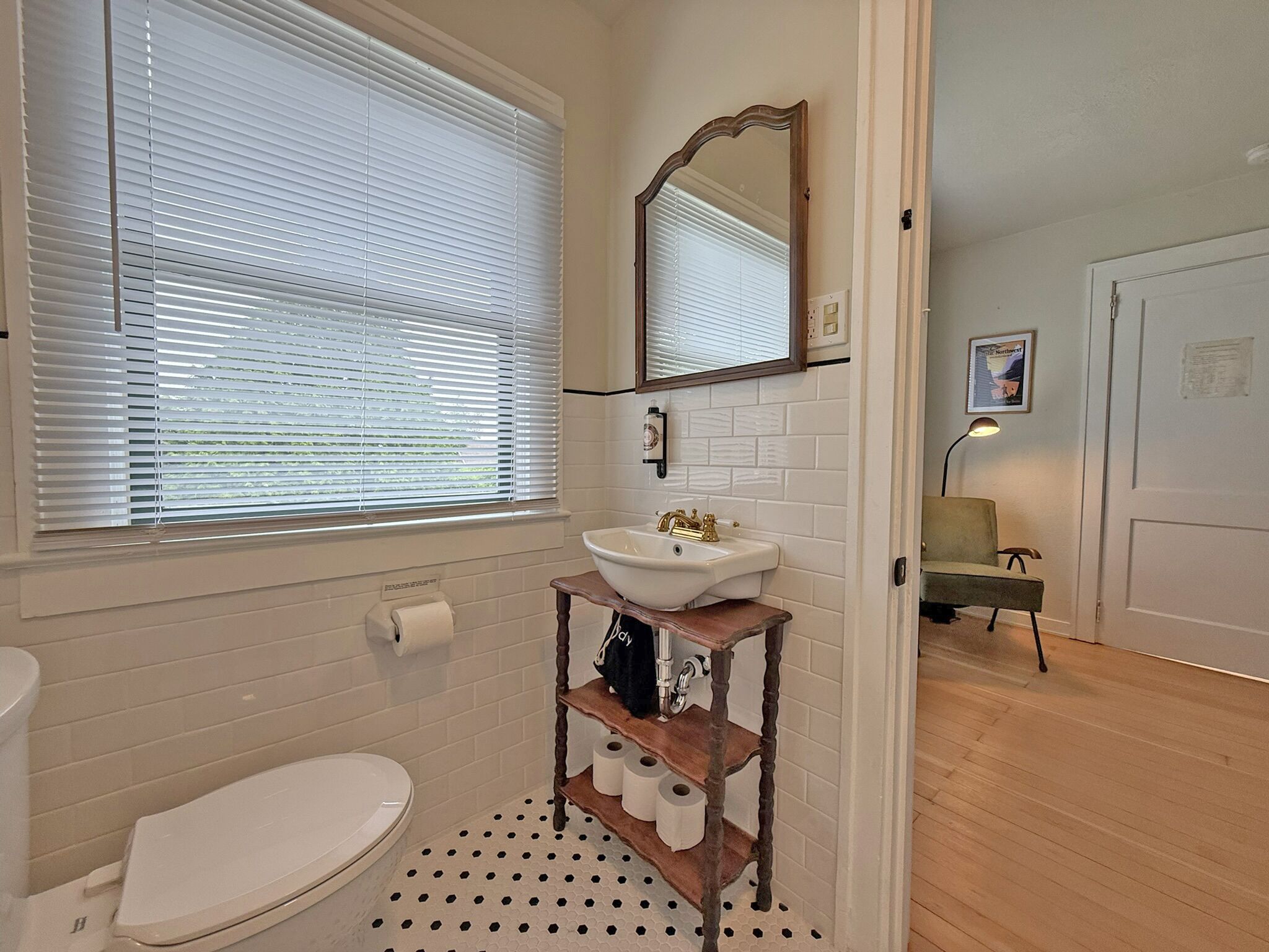 Et badeværelse med toilet, håndvask og et vindue med persienner.