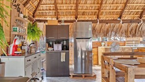 A rustic kitchen with a thatched roof, wooden cabinets, a stainless steel refrigerator, and a coffee bar. - Rancho Baja Unknown (El Sargento)