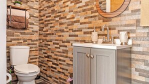 A bathroom with a tiled wall, a toilet, a sink with a mirror, and a cabinet. - Rancho Baja Unknown (El Sargento)