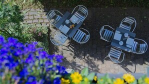 A patio with a table and chairs, surrounded by plants and flowers. - Reinhardts Garni Automobilia Hotel  (Bietigheim-Bissingen)