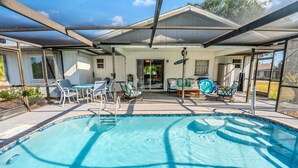 A covered outdoor pool area with a patio, seating, and a view of the house. - Charming 2BR Home w/Heated Pool & Arcade in Quiet Area – Perfect Location! (Port Charlotte)