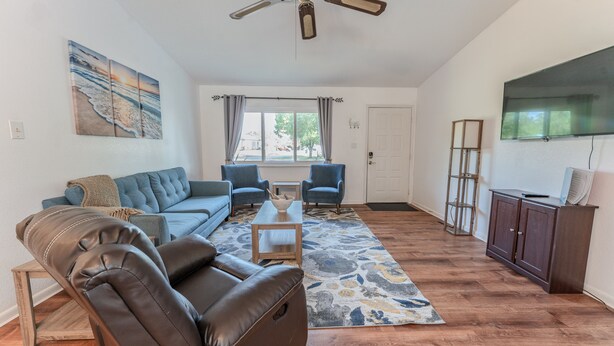 A living room with a sofa, two armchairs, a coffee table, a rug, a TV, and a cabinet. - Charming 2BR Home w/Heated Pool & Arcade in Quiet Area – Perfect Location! (Port Charlotte)