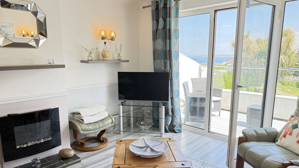 A living room with a fireplace, a TV, a wooden table, and a view of the outdoors.