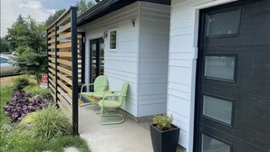 A modern house with a dark front door, a small porch with green chairs, and a wooden fence. - Modern Studio in Terrific Portland with AC, WiFi (Portland)
