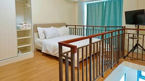 Ein Schlafzimmer mit Bett, Holzbalkon, Fernseher auf einem Tisch, Kleiderschrank und Klimaanlage.
