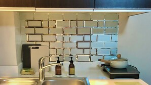 Eine moderne Küche mit einer Spüle aus Edelstahl, einem Seifenspender und einem Wasserkocher auf der Arbeitsfläche.