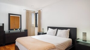 A modern bedroom with a large bed, dark nightstands, a mirror, and a window with curtains. - Lobos Horizon – Coziness with Madeiran Soul (Câmara de Lobos)