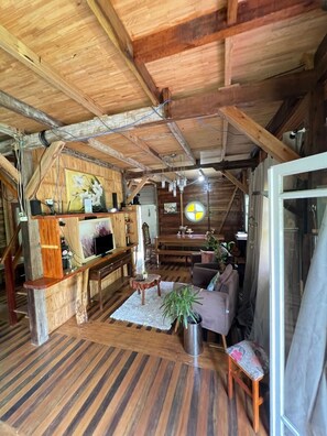 A rustic wooden interior with a dining area, a sofa, and a TV. - Comfort of nature (Aguas mornas)