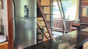 A kitchen with a stainless steel refrigerator, a black countertop, and a wooden ceiling structure. - Comfort of nature (Aguas mornas)