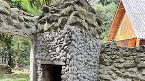 A stone structure with a small opening, possibly a fireplace, and a potted plant beside it. - Comfort of nature (Aguas mornas)