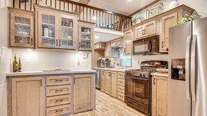A spacious kitchen with wooden cabinets, a stainless steel refrigerator, and a built-in oven. - Lakehouse with Sandy Beach and Boating (Belmont)