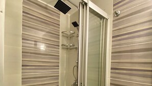 A modern bathroom with a glass-enclosed shower, a white sink, and striped wall tiles. - M4 Istiklal Spacious and Central 1+1 Apartment (Istanbul)