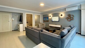 A modern living room with a grey sectional sofa, a coffee table, a TV, and a bookshelf. - M4 Istiklal Spacious and Central 1+1 Apartment (Istanbul)