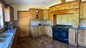 Una cocina con armarios de madera, una estufa negra y un salpicadero de azulejos.