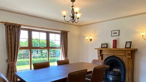 Un comedor con una mesa y sillas de madera, una chimenea y un amplio ventanal con cortinas.