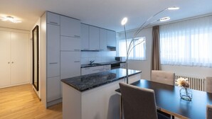 A modern kitchen with white cabinets, a granite countertop, and a dining area with a table and chairs. - Nice 1BR near lake and very cent - Hösch 13 (Zürich)