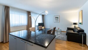 A modern kitchen with a marble countertop, a dining area with chairs, a sofa, and a small side table with a lamp. - Nice 1BR near lake and very cent - Hösch 13 (Zürich)