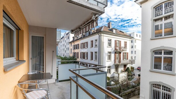A balcony with a table and chairs, overlooking a residential area with multi-story buildings. - Nice 1BR near lake and very cent - Hösch 13 (Zürich)
