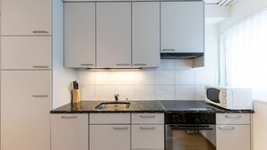 A modern kitchen with white cabinets, a granite countertop, a stainless steel sink, a microwave, and a built-in oven. - Nice 1BR near lake and very cent - Hösch 13 (Zürich)