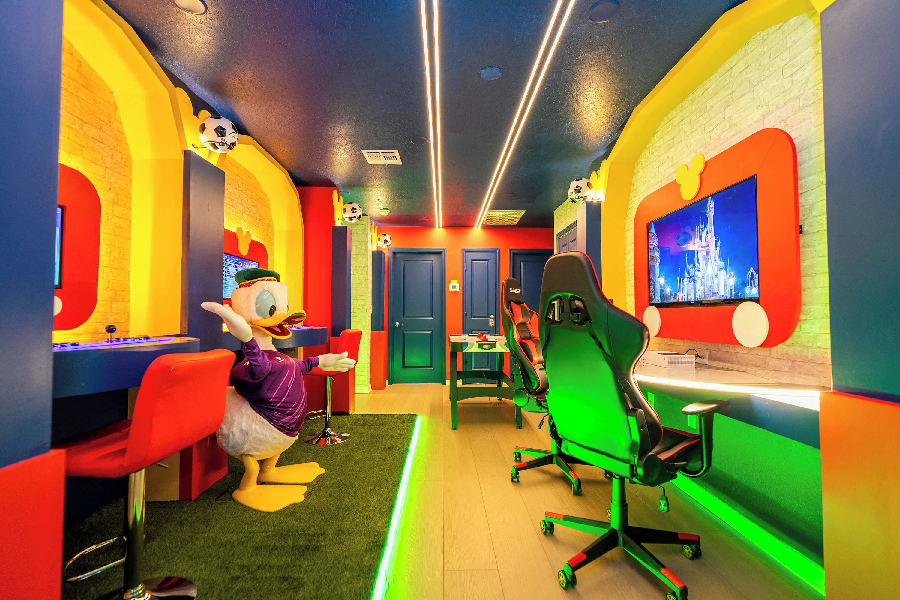 Um quarto vibrante com um mascote, uma escrivaninha, cadeiras e uma tela de televisão.